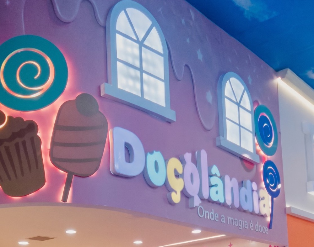 Fachada da loja Doçolândia, com o letreiro iluminado e os doces gigantes